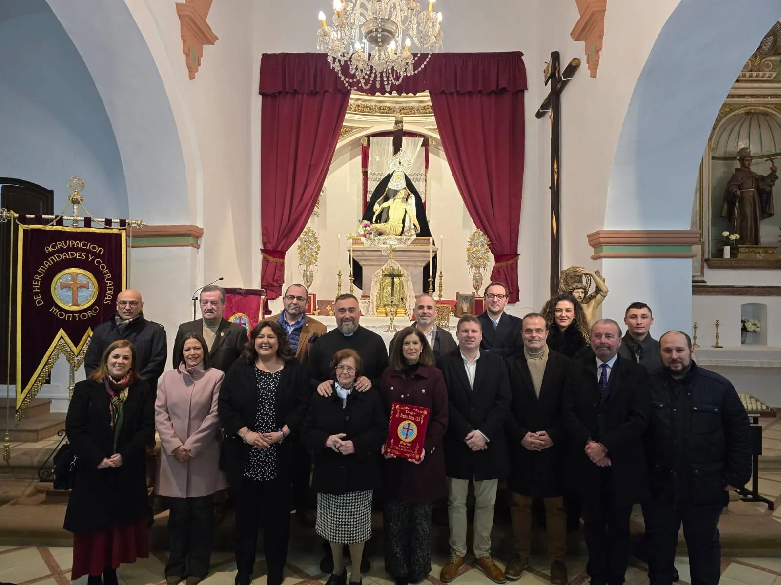 María José Román Cañas, en el cento de la imagen, recibe las pastas como pregonera de la Semana Santa 2026 en Montoro rodeada de familiares y la corporación municipal