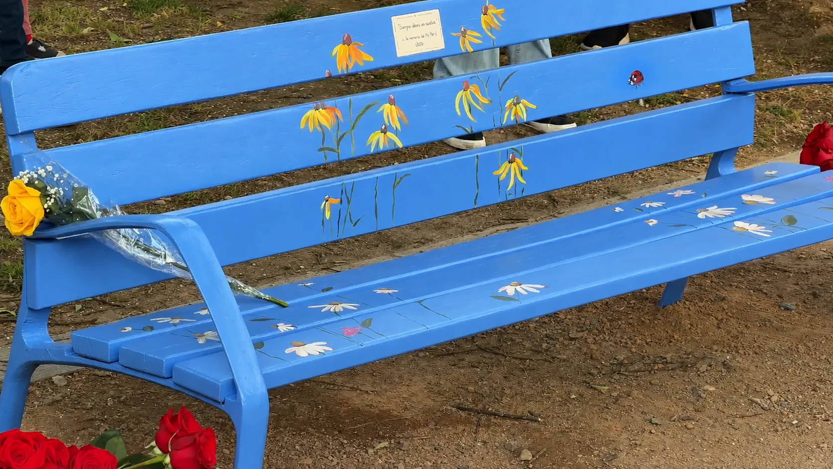 Banco azul con motivos florales en los Jardines de Orive de Córdoba, con una placa que reza: “Siempre estarás con nosotros, a la memoria de MC Abril”