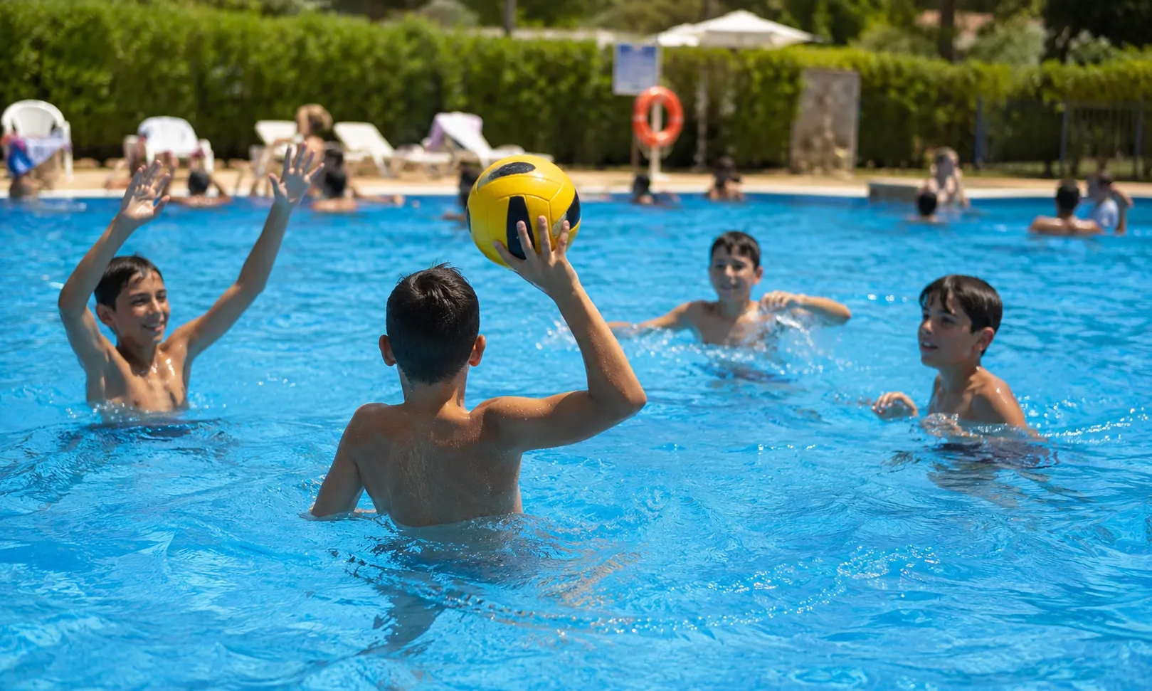 Niños jugando con una pelota en la piscina.