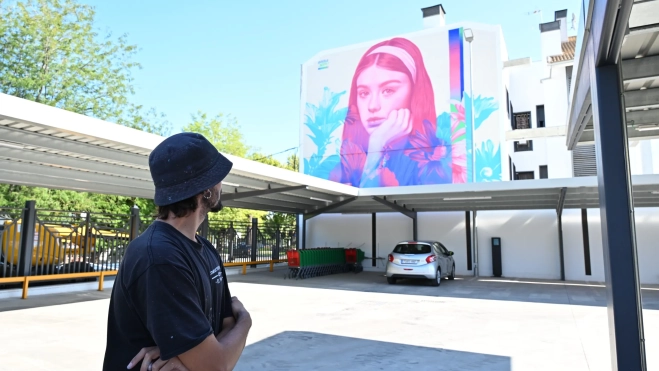 Jota López intercambiando miradas con su obra antes de viajar a su siguiente proyecto. Foto Ayuntamiento de Villa del Río.
